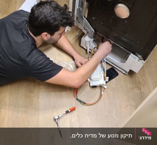 אדם מתקן מכשיר חשמלי עם כלים וחוטים